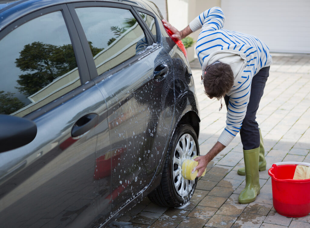 mężczyzna myje kołpak od samochodu